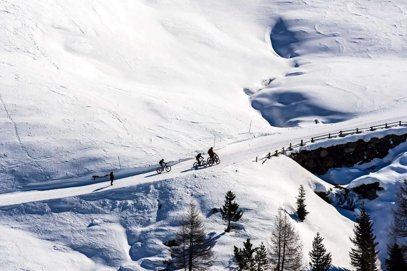 A picturesque view of cyclists traversing snowy mountains in South Tyrol, in the Dolomites of Italy.