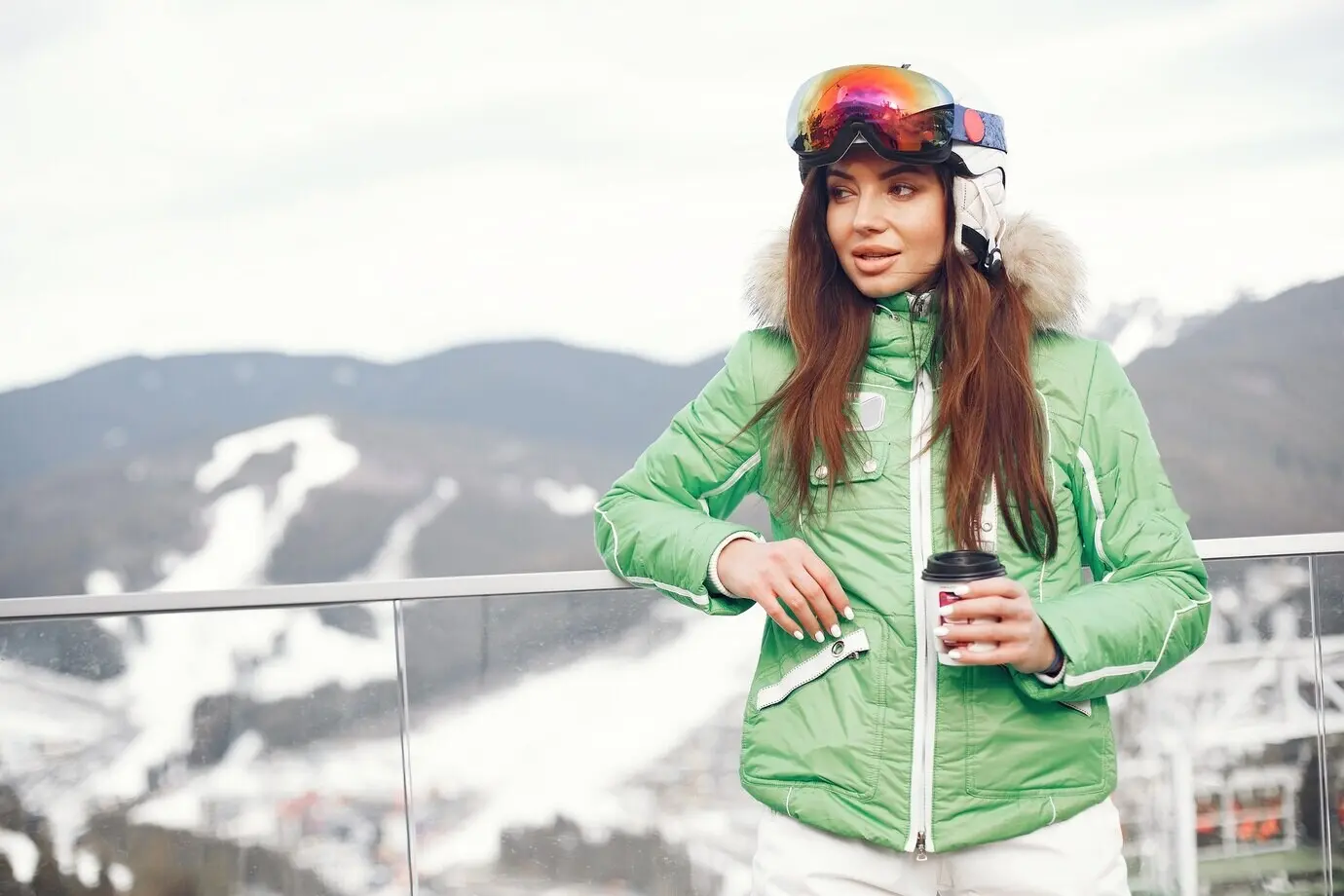 A woman in the mountains on a winter day, wearing a ski uniform.
