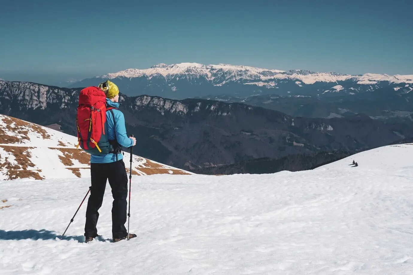 A stunning shot of a man hiking in Romania’s snow-covered Carpathian Mountains.